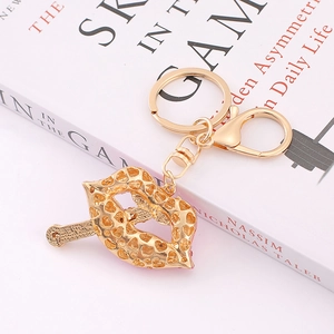 Golden metal lips keychain with heart cutouts and lobster clasp on book background