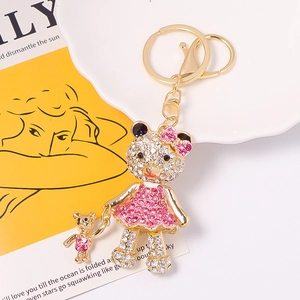 Golden metal bear keychain with sparkling pink and white rhinestones on a card