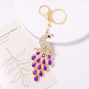 Elegant gold peacock keychain with crystal rhinestones and purple gemstones on white display