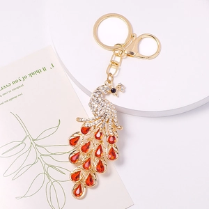 Detailed close-up of a peacock keychain with red and white rhinestones on gold alloy