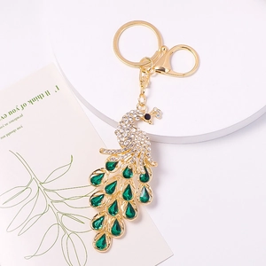 Detail of golden peacock keychain with green crystals and sparkling white rhinestones