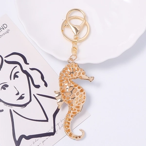Golden seahorse keychain with intricate scale texture and lobster clasp on white background