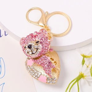 Portachiavi orsetto dorato con strass rosa e ciondolo a cuore su espositore bianco