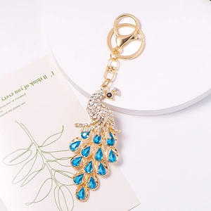 Detailed close-up of a golden peacock keychain with sparkling blue and white crystals