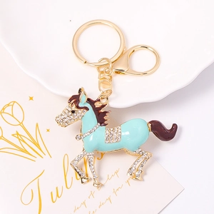 Détail d'un porte-clés cheval plaqué or avec émail bleu et strass blancs scintillants