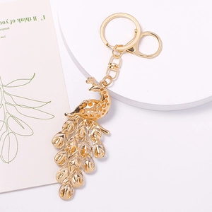 Golden peacock keychain with crystal accents and hollow metal craftsmanship on white background