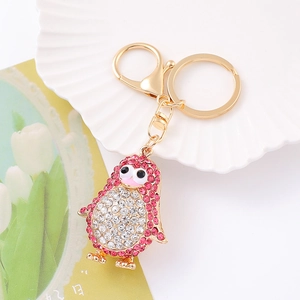 Détail du porte-clés pingouin en métal doré serti de strass roses et blancs