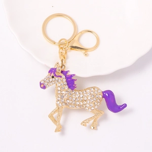 Sparkling crystal pony keychain in gold metal with purple accents on decorative plate