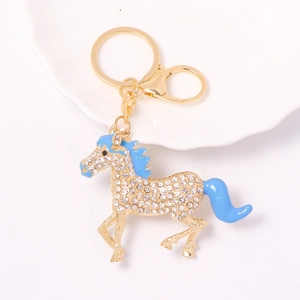 Detailed view of horse keychain with white rhinestones and blue enamel on a ceramic plate