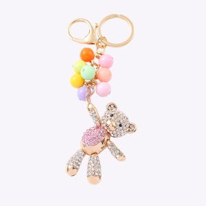 Gouden teddybeer sleutelhanger met roze strassteentjes en gekleurde kralen op witte basis