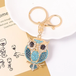 Detail of owl keychain featuring blue rhinestones and gold-plated alloy finish