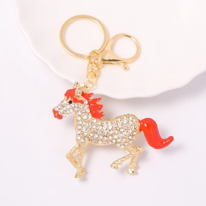 Golden horse keychain with sparkling rhinestones and red enamel finish on white plate