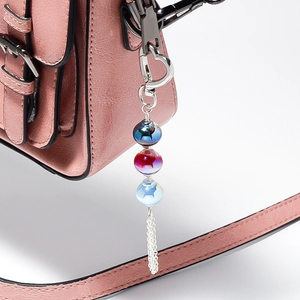 Close-up of luminous lantern beads with silver metal tassel on a pink leather bag