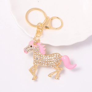 Detail shot of a golden horse keychain with white rhinestones and pink enamel finish