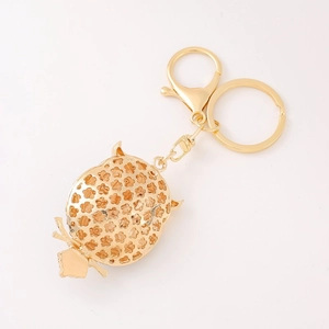 Close-up of golden owl keychain featuring intricate floral hollow carving and dual metal rings