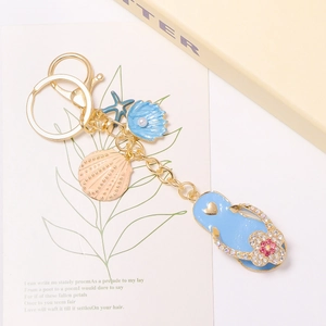 Blauwe slipper sleutelhanger met zeester, schelp en strass op een gouden ring