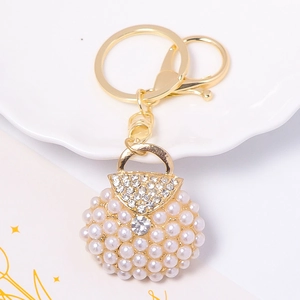 Detailed close-up of a pearl-encrusted handbag keychain with gold metal ring and rhinestones