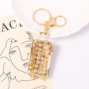 Porte-clés valise dorée avec strass sur une assiette décorative blanche