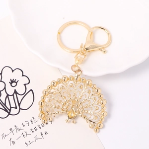 Golden peacock rhinestone keychain featuring hollow engraved feathers and metal lobster clasp