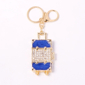 Porte-clés valise doré avec émail bleu et strass scintillants sur fond blanc pur