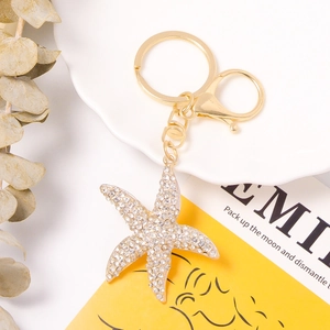 Detailed view of starfish keychain with clear rhinestones on white ceramic plate