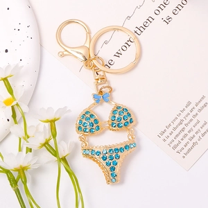 Close-up of golden bikini keychain with blue rhinestones and cute bow on a card
