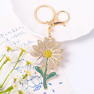 Macro detail of sunflower keychain with white, yellow and green rhinestones on gold alloy
