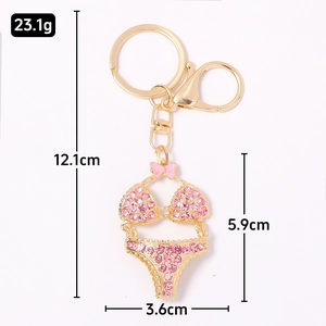 Pink rhinestone bikini keychain with gold metal base and bow decoration on white background