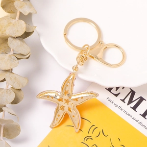 Golden starfish keychain with pink accents and rhinestone details on a white dish