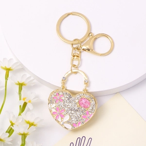 Close-up of heart keychain with pink enamel flowers and sparkling rhinestones on white display