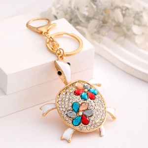 Zinc alloy turtle keychain with colorful rhinestone flowers on a white geometric stand