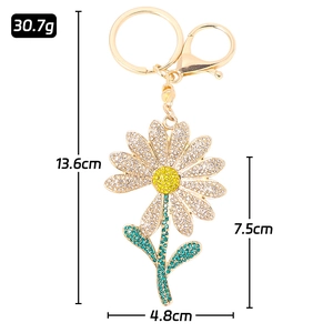 Daisy rhinestone keychain with white and green crystals in gold metal, 13.6cm height