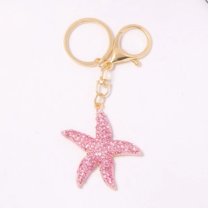 Pink rhinestone starfish keychain with gold alloy keyring and lobster clasp on white background