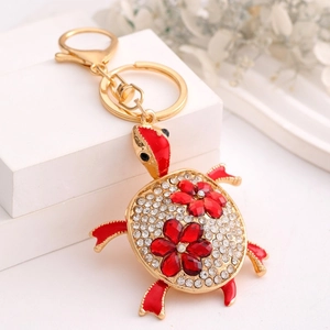 Detailed close-up of a rhinestone sea turtle keychain with red flowers and gold finish