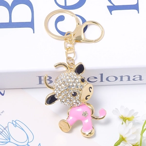 Detail of pink enamel cow keychain with white rhinestones on a gold-plated clasp