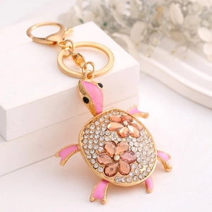 Detailed close-up of a sparkling turtle keychain with white rhinestones and pink crystal flowers