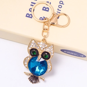 Golden owl keychain with blue crystal abdomen and sparkling rhinestones on a gift box