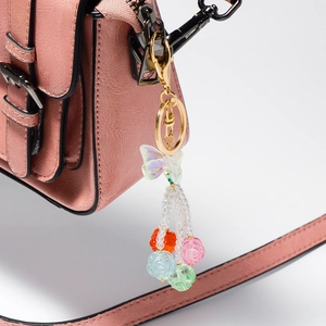 Iridescent acrylic butterfly keychain with colorful resin roses on a pink leather bag