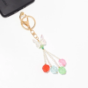 Detailed shot of acrylic butterfly charm with colorful floral resin beads and gold clasp