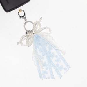Detail of blue lace ribbon and white pearl bow pendant for phone and bags