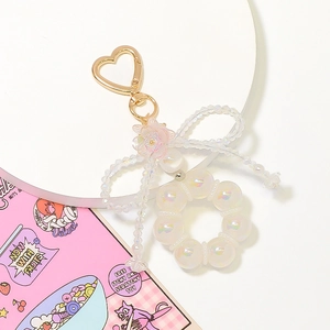 Macro detail of heart-shaped gold hook with pink flower and iridescent pearl beads