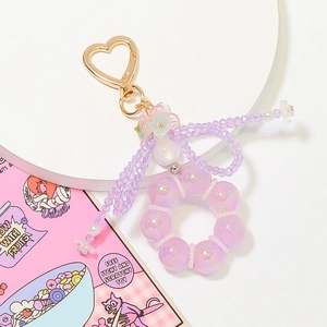 Macro detail of purple iridescent beaded keychain with golden heart clasp and floral charm