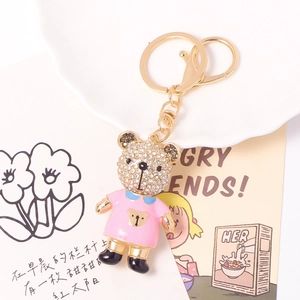 Detail eines süßen Teddybär-Schlüsselanhängers mit rosa Emaille-Kleid und Strass