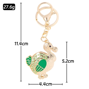 Golden metal dodo bird keychain with green enamel and rhinestones on white background