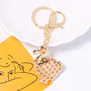 Golden metal duck keychain with sparkling rhinestone accents on a white decorative tray