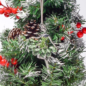 Detail of ballerina Christmas ornament with green crystals hanging on a festive pine tree branch