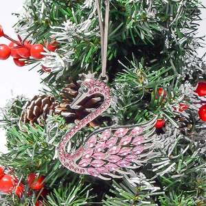 Detail of pink swan pendant with sparkling rhinestones hanging on a Christmas tree branch