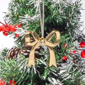 Gros plan d'un pendentif nœud de Noël doré avec pierre précieuse sur branche enneigée