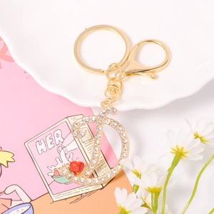 Detailed macro of golden letter D keychain with sparkling crystals and red heart charm