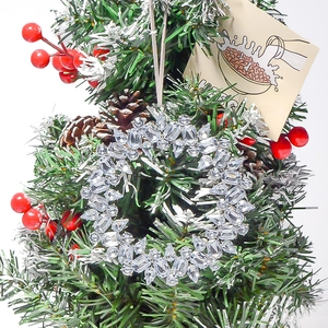 Macro detail of a crystal wreath pendant with sparkling rhinestones on a Christmas tree branch